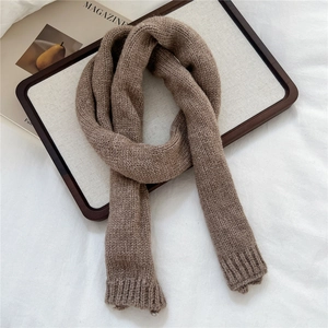 Detail of a brown chunky knit scarf showing soft texture and ribbed edges on white fabric