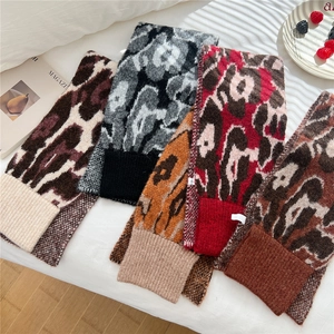 Flat lay detail of leopard print knitted scarves in multiple colors on a bed