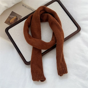 Detail of caramel brown knit scarf with ribbed edges on a minimalist tray