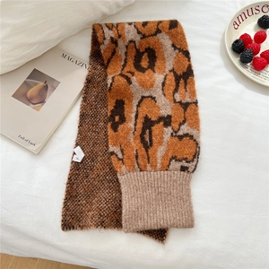 Detail view of leopard print knit scarf with ribbed edges on a white fabric surface