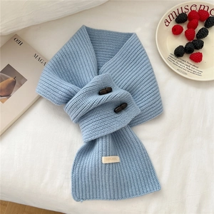 Détail montrant la texture en tricot 100% laine et les boutons en bois de l'écharpe bleue