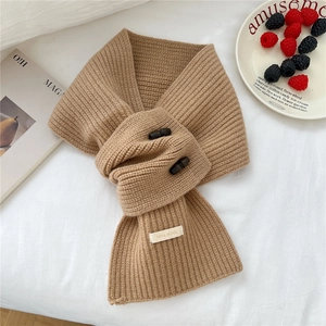 Détail d'une écharpe en laine camel avec boutons en bois et étiquette 100% laine