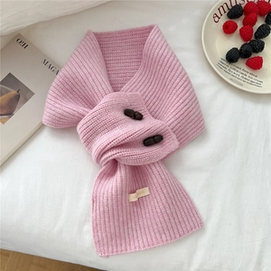 Détail d'une écharpe en laine rose avec boutons en corne et étiquette 100% laine