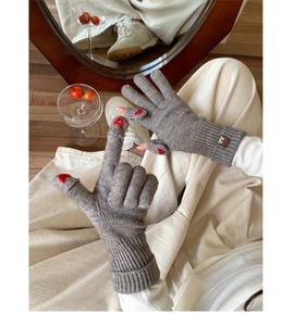 Dettaglio di guanti in maglia grigi con ricamo a cuore rosso sulle punte touch screen