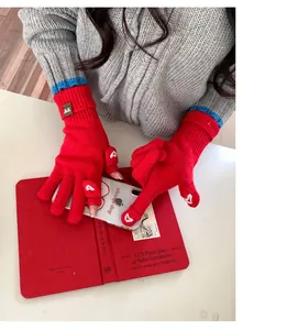 Dettaglio guanti in maglia rossi con cuore ricamato e polsini a righe blu eleganti