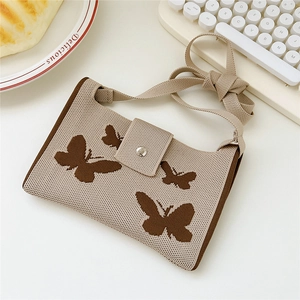 Detailed knit shoulder bag with butterfly pattern shown next to cake and keyboard