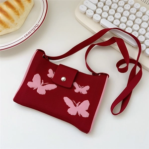 Detail of red knitted crossbody bag with pink butterfly and magnetic metal buckle closure