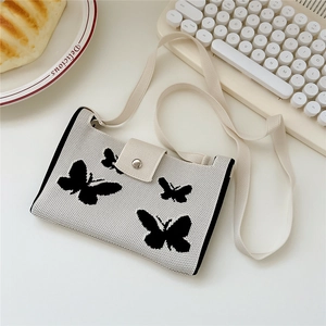Close-up of knit crossbody bag with butterfly patterns and silver magnetic clasp