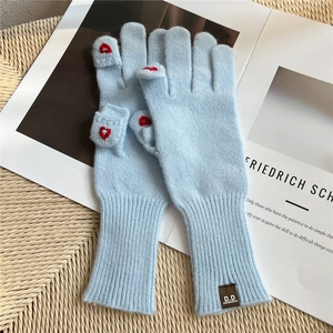 Dettaglio guanti in maglia azzurro con ricamo a cuore e design a conchiglia