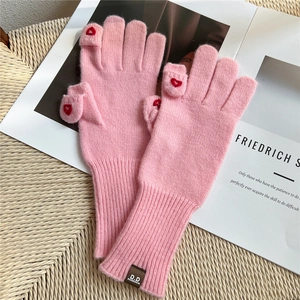 Dettaglio di guanti rosa in maglia con design a dita scoperte e cuore ricamato