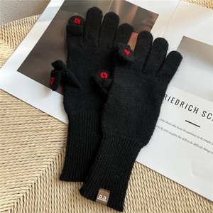Dettaglio guanti in maglia nera con ricamo a cuore e design a dita scoperte