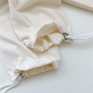 Detail of adjustable drawstring cuff on cream sun protection sleeves with plastic toggle