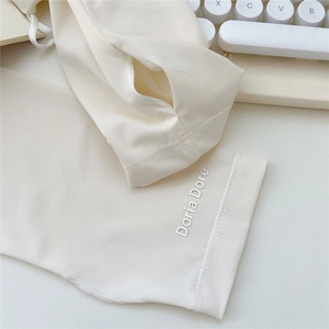 Close-up of cream sun protection arm sleeves featuring a brand logo and finger hole