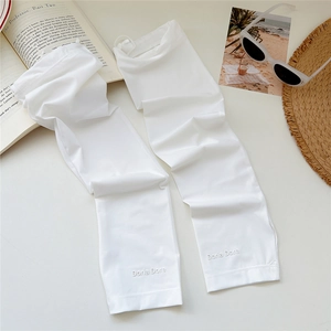 Close-up of white sun protection arm sleeves with logo detail and travel accessories