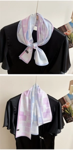 Detail of a pastel geometric polyester silk scarf tied on a black satin ruffled blouse