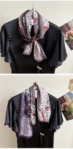 Detail of silk scarf with zebra print and letters tied on a black satin blouse