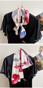 Artistic floral silk scarf tied in a bow on a black dress, showing satin texture