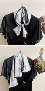Detail of floral printed silk scarf tied on a black satin top with a pearl button accent