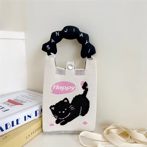 Détail du sac tricoté avec motif de chat et poignée nuage posé sur des livres
