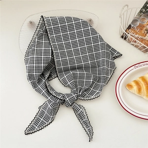 Gros plan du foulard à carreaux avec bords festonnés noirs sur décor de table blanc