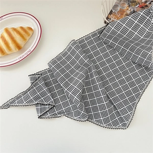 Détail d'un foulard à carreaux noir et blanc avec bordures en dentelle ondulée chic