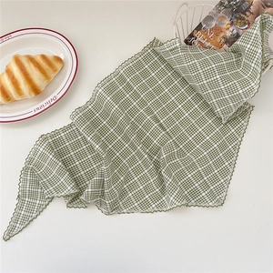 Détail du foulard en coton à carreaux vert et blanc avec bordure ondulée et style français