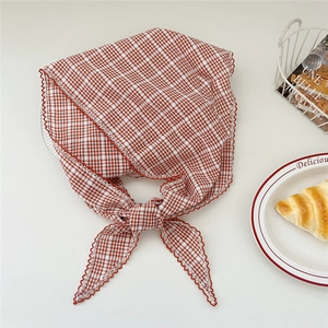 Détail d'un foulard en vichy rouge avec bordures en dentelle crochetée et un nœud décoratif