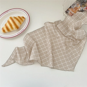 Détail d'un foulard en coton lin à carreaux marron avec bords ondulés raffinés