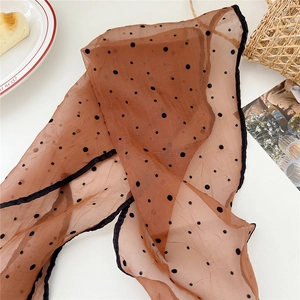 Detailed close-up of a vintage polka dot sheer scarf with elegant black stitched edges