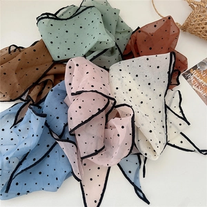 Close-up of colorful polka dot organza scarves in mint, pink, and caramel with fine edging