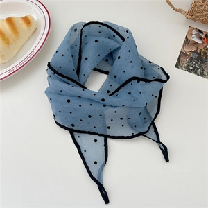 Macro detail of light blue polka dot silk scarf with black piping on white background