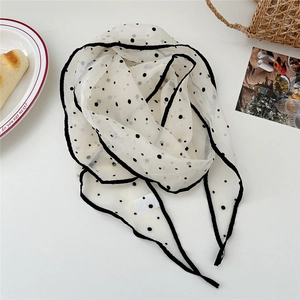 Close-up of lightweight polka dot silk scarf with black piping on a picnic setting