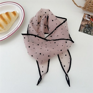 Close-up of light pink polka dot chiffon scarf with delicate black wavy edges on a table