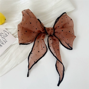 Close-up of a brown polka dot organza bow scarf with long ribbons on a stylist background
