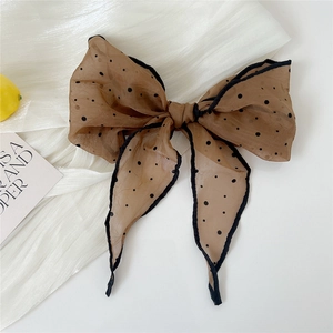 Close-up of a brown polka dot organza bow scarf with black edges on white fabric