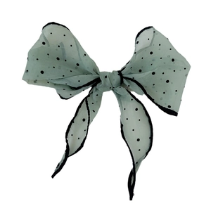 Green polka dot sheer bow hair accessory with black trim on a clean white background