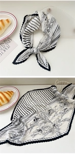 Detailed view of black and white pleated scarf with floral print and stripe texture