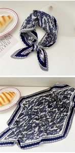 Detail of blue and white pleated silk scarf with vintage French pattern on white table