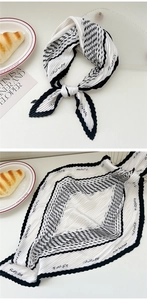 Detailed view of black and white pleated silk scarf with flower text and geometric pattern