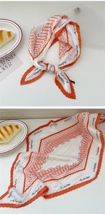 Detail of pleated orange silk scarf with black FLOWER letter print and wavy texture