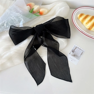 Dettaglio di un fiocco in chiffon plissettato nero su seta bianca con tulipani