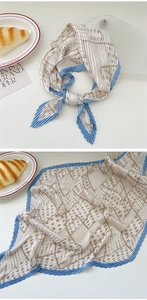 Macro detail of pleated silk scarf with beige geometric patterns and blue jagged edges