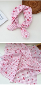 Detail of pink plaid cotton scarf featuring a red bow print and soft fabric texture