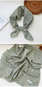 Detailed view of sage green cotton scarf with vintage feather prints and 100% cotton label