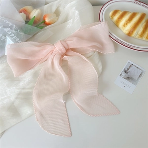 Dettaglio del nastro in chiffon rosa a pieghe con trama su sfondo di seta bianca