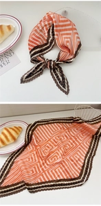 Detail of pleated orange silk scarf with geometric maze pattern and striped border
