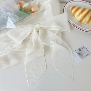 Dettaglio di sciarpa in chiffon plissettato bianco crema annodata a fiocco con trama fine