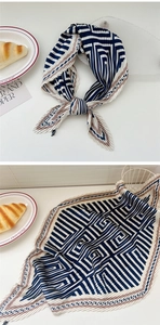 Detailed close-up of pleated silk scarf featuring geometric navy and beige patterns