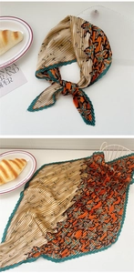 Detail of pleated silk scarf showing orange and green floral patterns with accordion folds