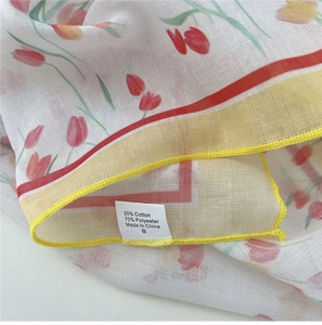 Detail of red tulip prints on breathable cotton linen fabric with yellow stitched edges